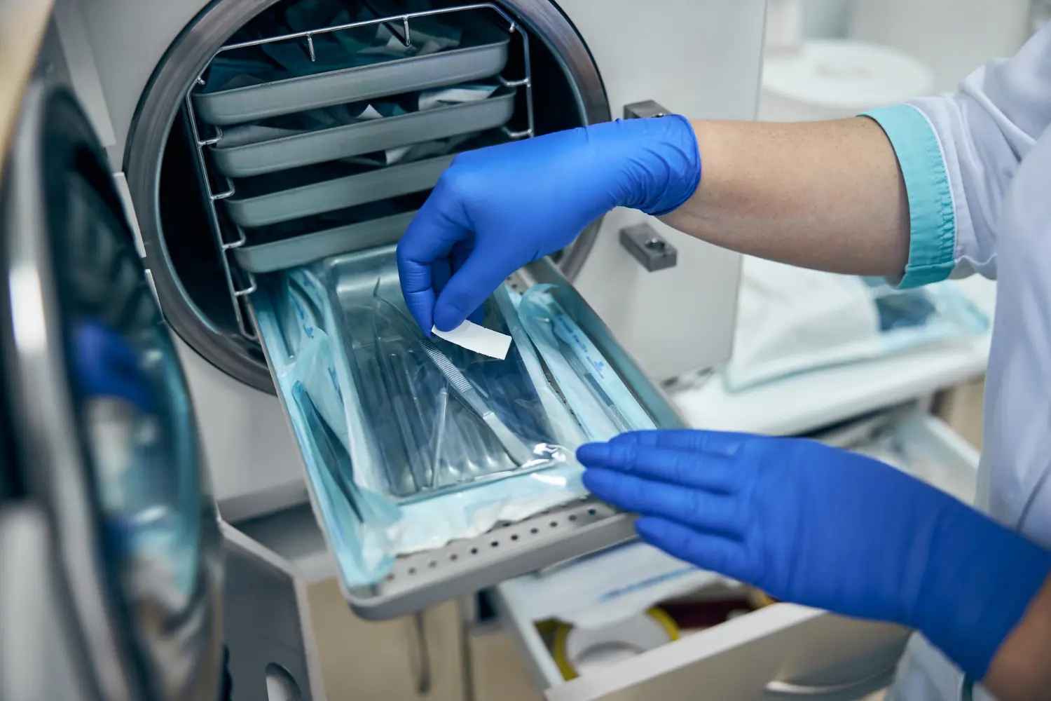 Profissional de saúde coloca instrumentos na autoclave para esterilização de materiais hospitalares