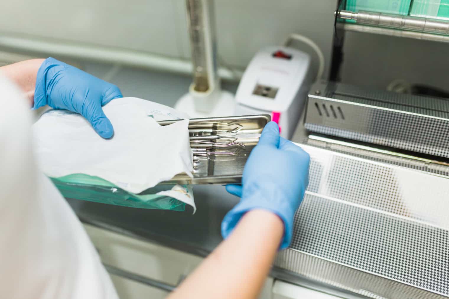 Profissional abrindo embalagem de instrumentos após desinfecção e esterilização para uso em procedimento