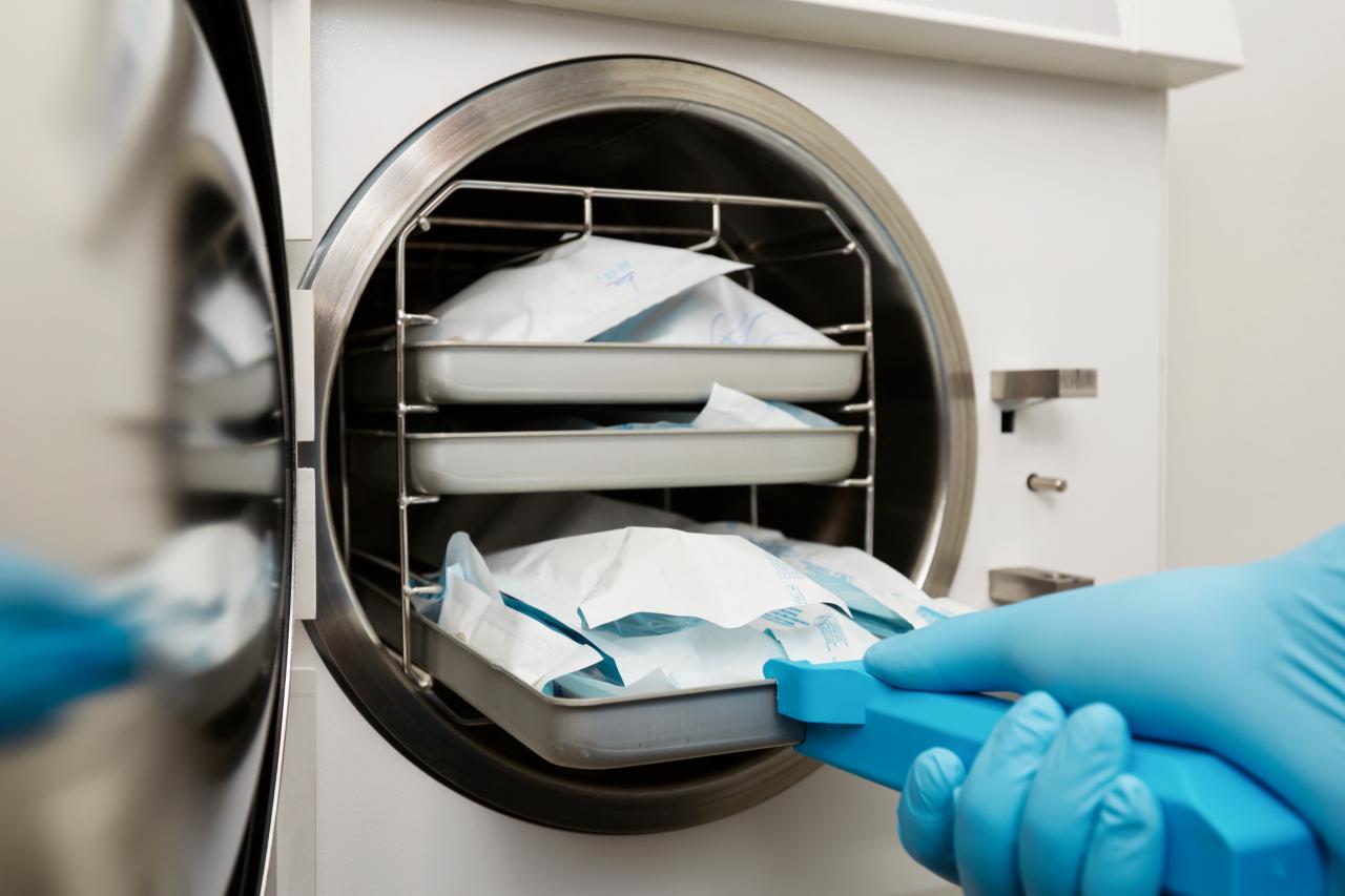 Profissional manuseia autoclave na Central de Material e Esterilização com materiais embalados