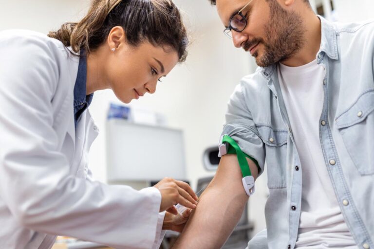 Profissional realiza coleta de sangue em paciente com garrote no braço em ambiente clínico